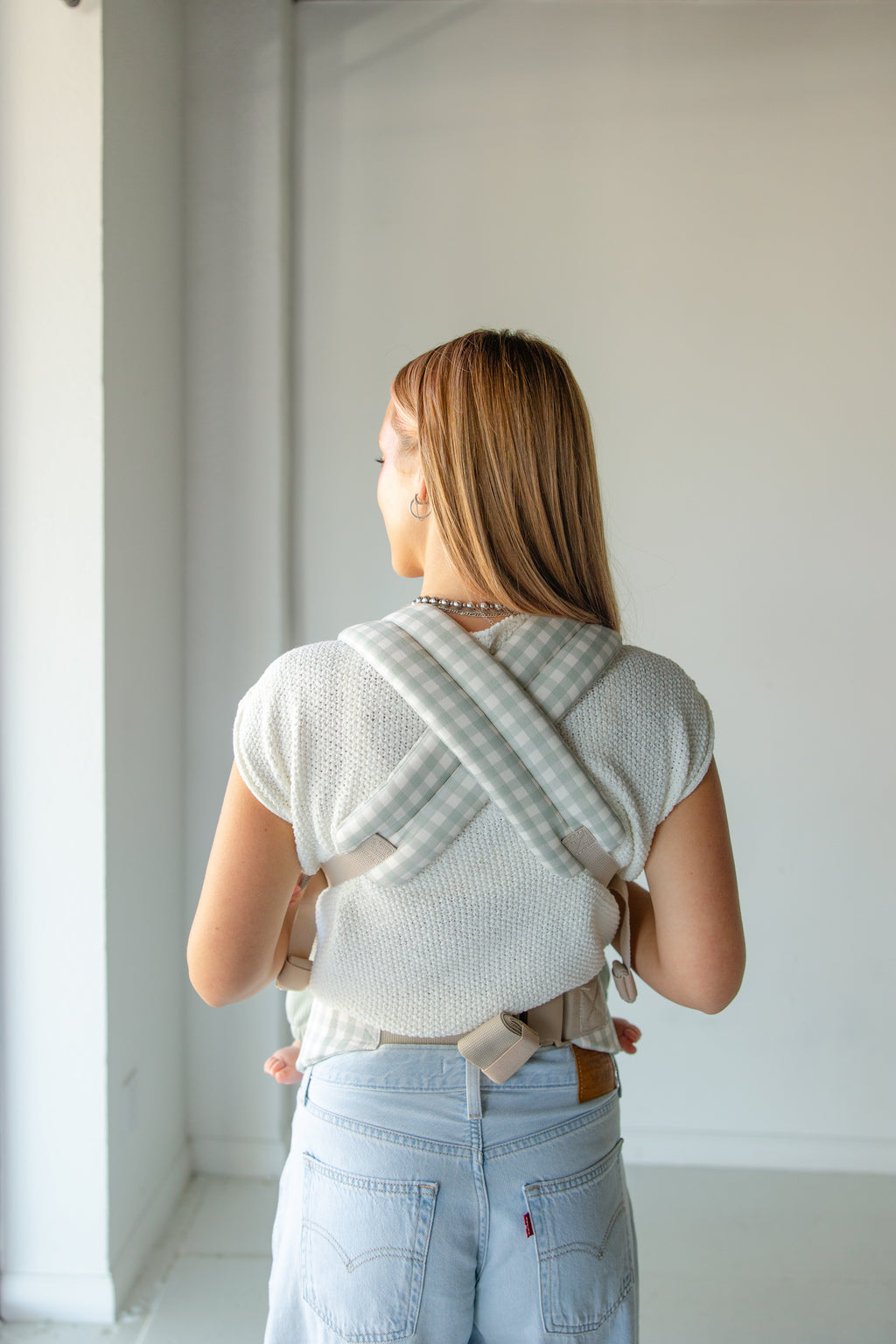 Coco Gingham Baby Carrier by Coco Carriers with a front pocket, adjustable straps, and ergonomic design for comfortable babywearing.