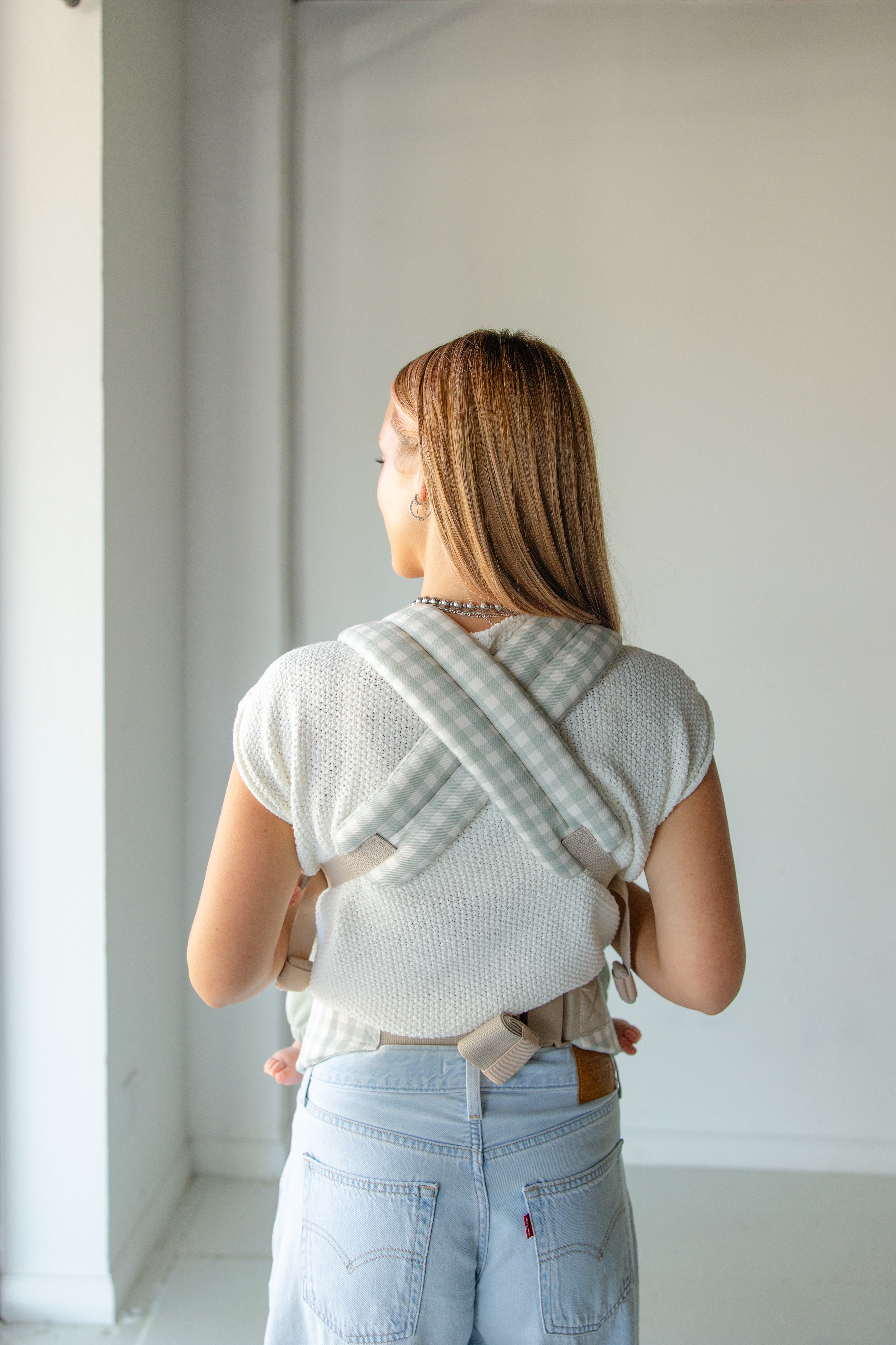Coco Gingham Baby Carrier by Coco Carriers with a front pocket, adjustable straps, and ergonomic design for comfortable babywearing.