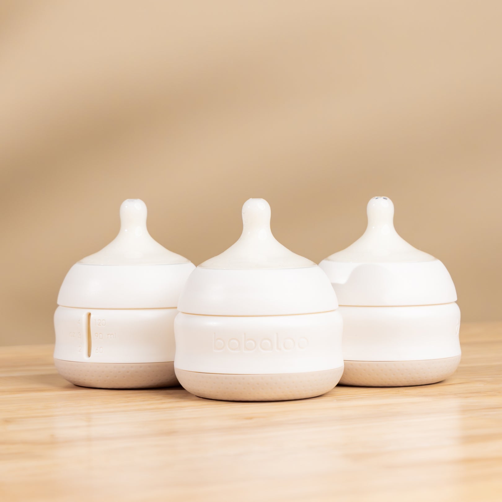 Set of three Babaloo baby bottles with colorful silicone sleeves and clear glass bodies, designed for easy grip and feeding.
