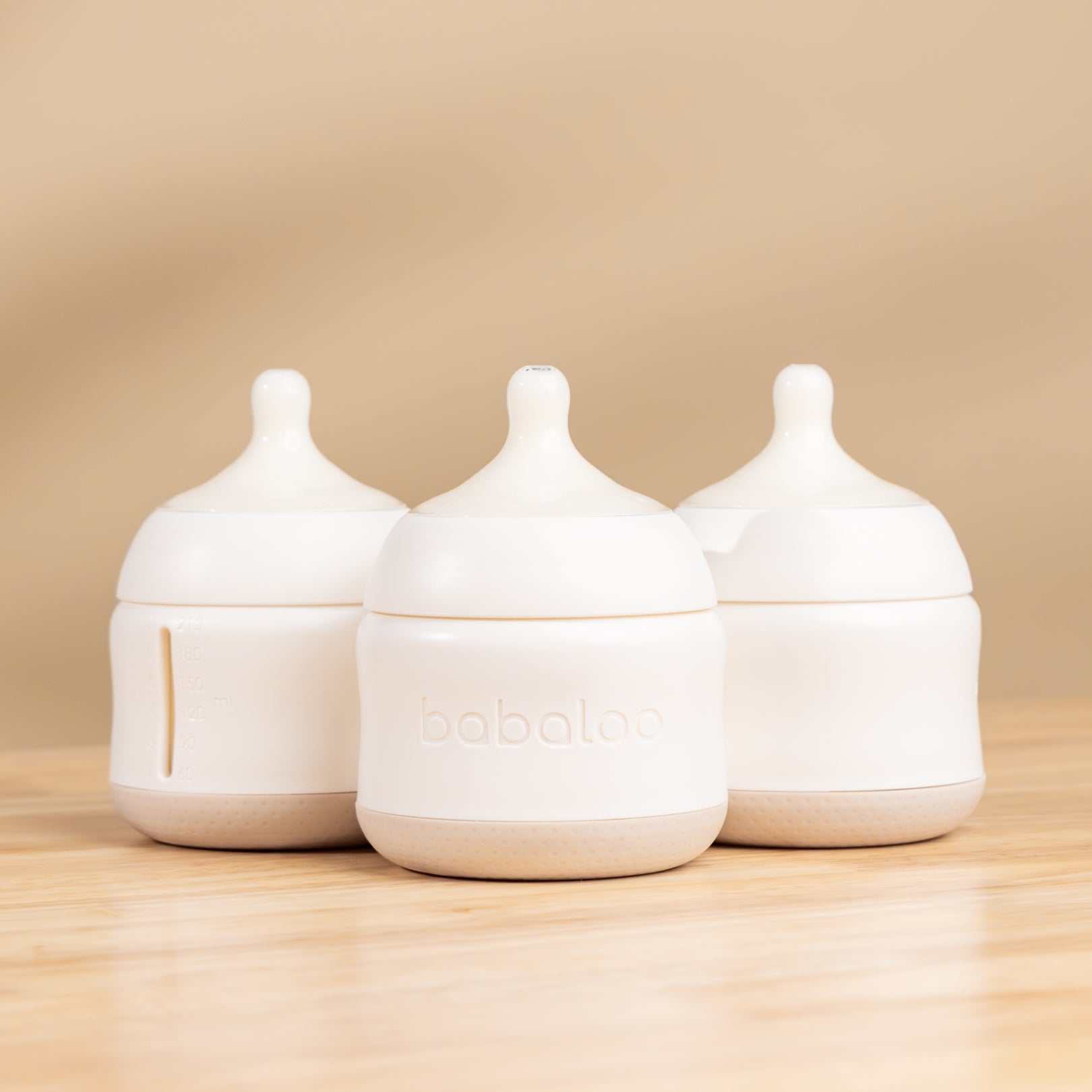 Set of three Babaloo baby bottles with colorful caps and clear plastic bodies, designed for infant feeding.